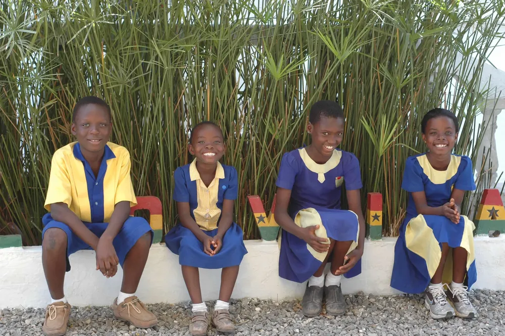 Four Lovia pupils sitting together and laughing beside a painted LOVIA sign.