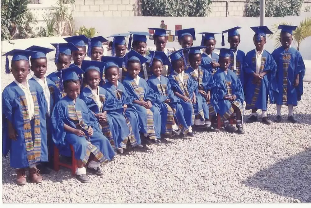 A Lovia graduating class in blue gowns and kente stoles.